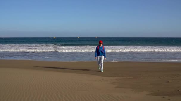 Active hiker woman walks on the beach from the water. Caucasian young woman with backpack on Tenerife, Canary Islands, Spain — Stock Video