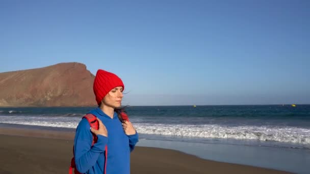 Actieve wandelaar vrouw wandelingen op het strand. Kaukasische jonge vrouw met rugzak op Tenerife, Canarische eilanden, Spanje — Stockvideo