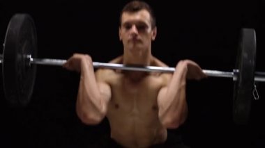 Adam bir halter egzersiz yapıyor, bir crossfit stüdyoda siyah bir arka plan üzerinde çalışmaktadır