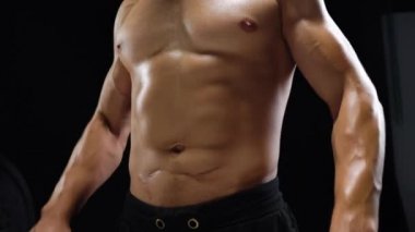 Adam bir halter alıştırmalar stüdyoda siyah bir zemin üzerine eğitim yapıyor