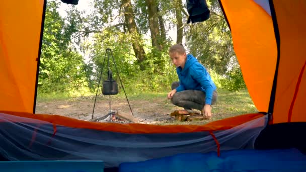 Bir turist çadır - bir kadın görünümünden yakacak odun çaydanlık ısıtılan bir ateşe koyar. — Stok video