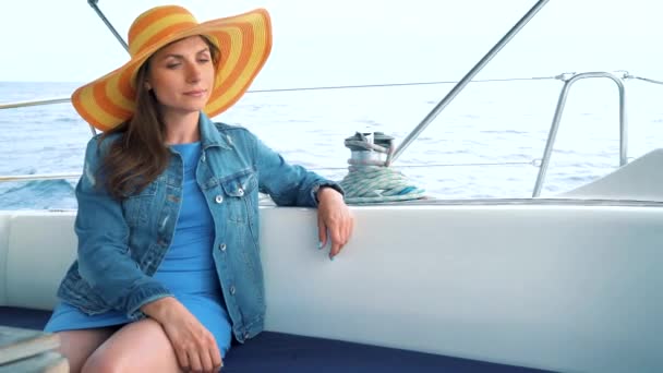 Kvinna i en gul hatt och blå klänning flicka vilar ombord på en yacht på sommarsäsongen på ocean — Stockvideo