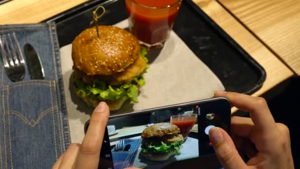 女孩做了一个汉堡和番茄汁的照片, 在咖啡馆关闭智能手机 — 图库视频影像