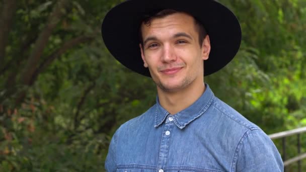 Joven hombre hipster en sombrero riendo, relajado delante de la cámara — Vídeo de stock