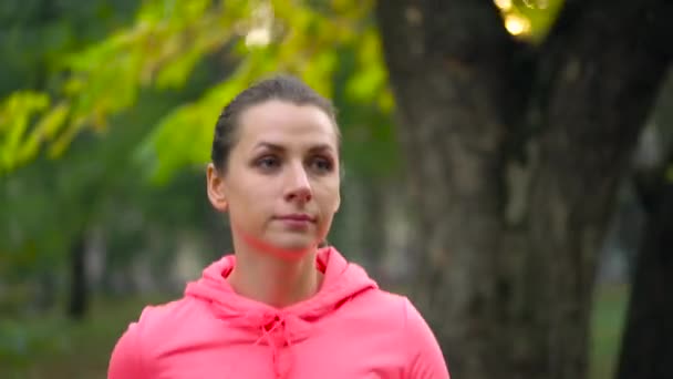 Primer plano de una mujer corriendo por un parque de otoño al atardecer. Movimiento lento — Vídeos de Stock