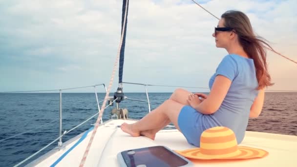 Woman in a yellow hat and blue dress rests aboard a yacht on summer season at ocean. Slow motion — Stock Video