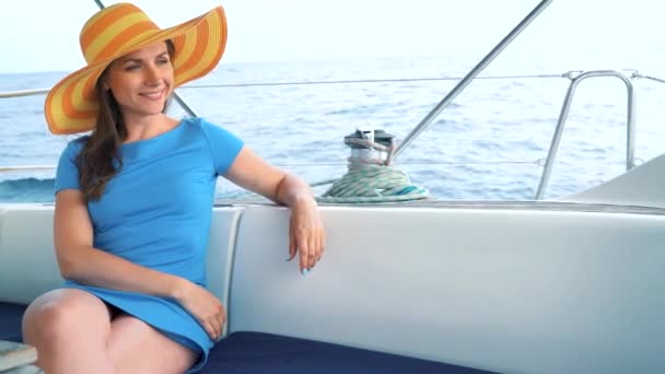 Frau mit gelbem Hut und blauem Kleid ruht an Bord einer Jacht zur Sommersaison auf hoher See — Stockvideo