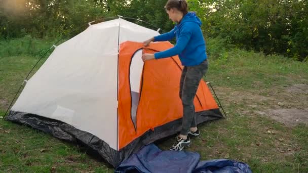 Kobieta jest wprowadzenie turystyczny namiot w lesie o zachodzie słońca — Wideo stockowe