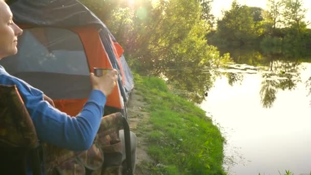 Femme boit du thé dans un fauteuil près d'une tente sur la rive de la rivière — Video
