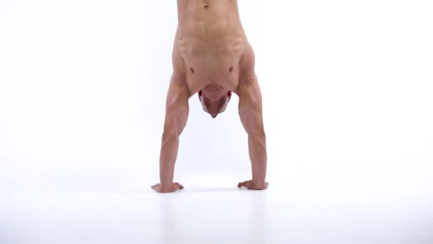 Homem homem se levanta e anda em seus braços, está envolvido em uma crossfit em um fundo branco no estúdio — Vídeo de Stock