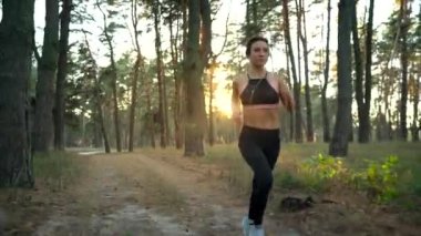 Kadın bir sonbahar orman günbatımında çalışan kulaklıklar ile kapatın. Farklı hızlarda - normal ve yavaş filme