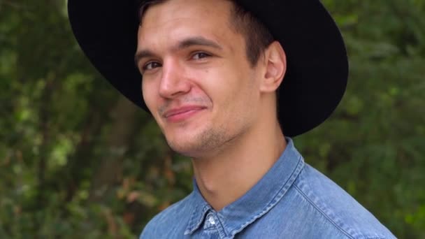 Junger Hipster mit Hut lacht, entspannt vor der Kamera — Stockvideo