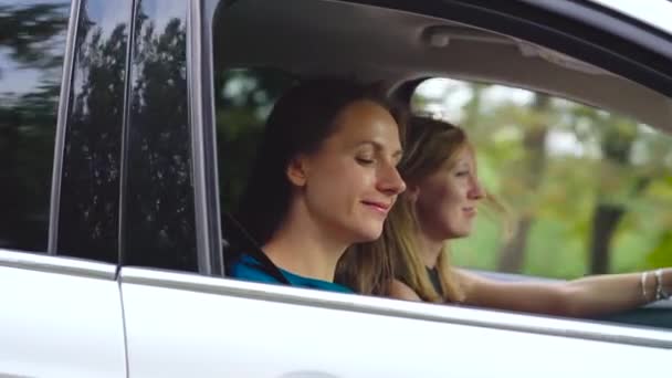 Duas jovens andam de carro e divertem-se. Um deles tira uma foto de si mesmo em uma câmera de filme. Movimento lento — Vídeo de Stock