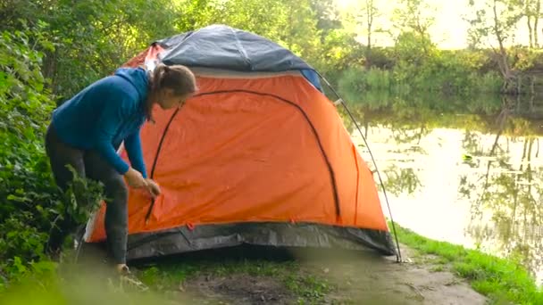 Žena je uvedení turistický stan na břehu řeky — Stock video