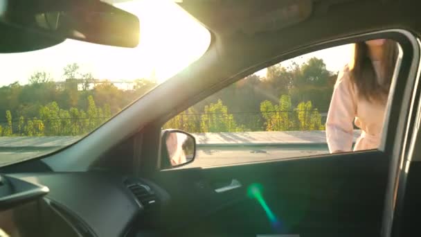 Hermosa chica pone un abrigo en el asiento del coche y se mete en el coche, se sujeta el cinturón de seguridad, a punto de alejarse . — Vídeos de Stock