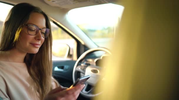 Kvinna i glasögon talar på smartphone och dricker kaffe i bilen — Stockvideo