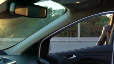 Kadın alışveriş torbaları üzerinde bir araba koltuğu koyar ve o, uzaklaştırmak isteyen oturur.