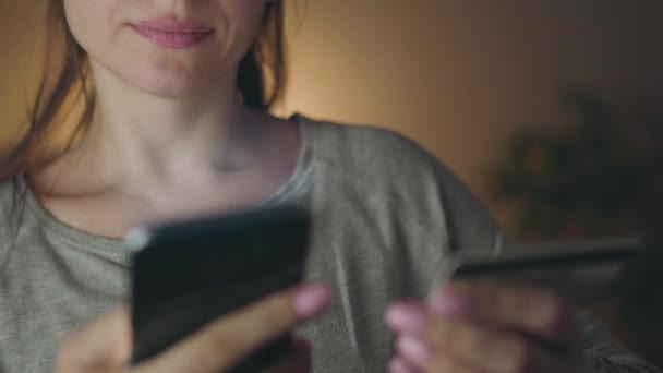 Kvinna gör online betalning hemma med ett kreditkort och smartphone — Stockvideo