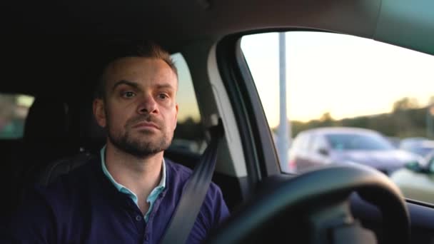 Чоловік водить машину, шукає місце для паркування — стокове відео