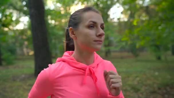 Primo piano di una donna che corre attraverso un parco autunnale al tramonto — Video Stock