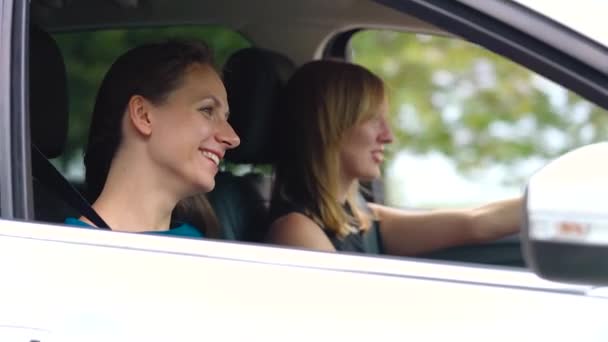 Dos mujeres jóvenes viajan en un coche y se divierten. Movimiento lento — Vídeos de Stock