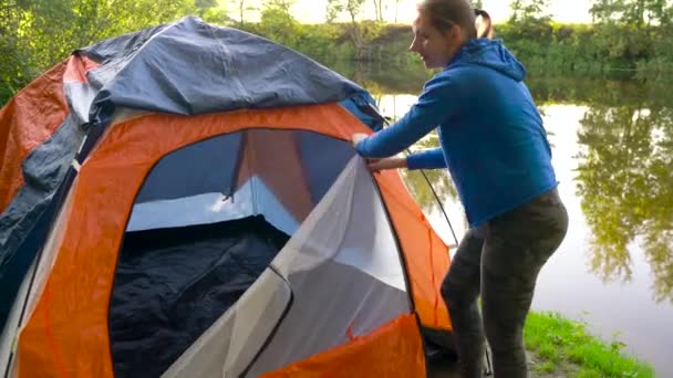 Kadın turist çadır nehir kıyısında koyuyor — Stok video