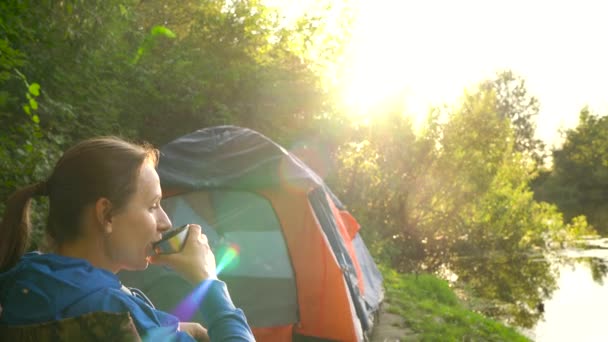 Kvinnan dricka te i en fåtölj nära ett tält på Älvstranden — Stockvideo