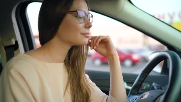 Portret van een mooi meisje in glazen in de auto — Stockvideo