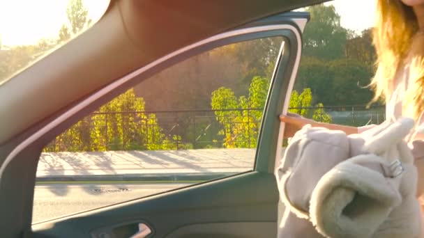 Schöne Mädchen legt einen Mantel auf den Autositz und steigt ins Auto, schnallt den Sicherheitsgurt an, um loszufahren. Zeitlupe — Stockvideo