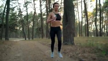 Sonbahar bir ormandan günbatımında çalışan kulaklıklar ile kadın yakın çekim