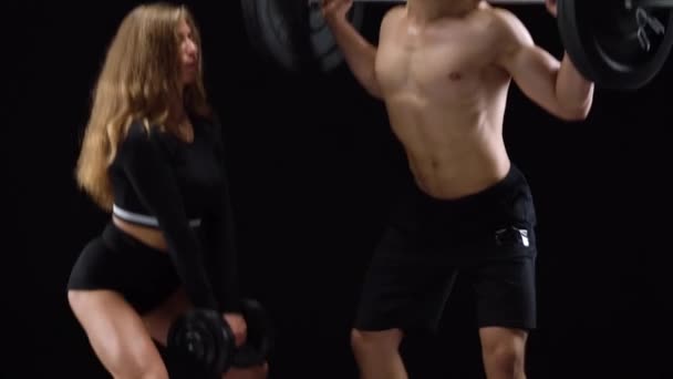 athletische Männer und Frauen hocken mit zusätzlichem Gewicht und trainieren ihre Beine und Po auf schwarzem Hintergrund im Studio