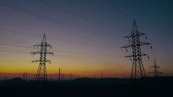 Vista da altura das silhuetas da linha de energia contra o céu do por do sol — Vídeo de Stock