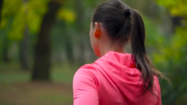 Close up de mulher correndo através de um parque de outono ao pôr do sol, vista para trás. Movimento lento — Vídeo de Stock