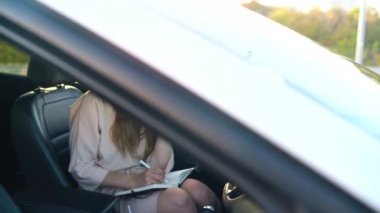 İş kadın bir smartphone ve arabada oturan günlük Not almak söz