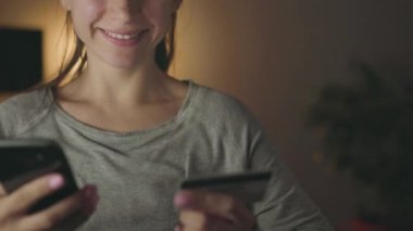 Kadın evde smartphone bir kredi kartı ile online ödeme yapar