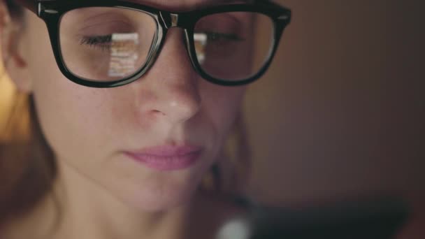 Femme en lunettes regardant sur l'écran du smartphone et surfant sur Internet — Video