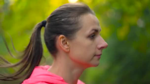 Primer plano de una mujer corriendo por un parque de otoño al atardecer. Movimiento lento — Vídeos de Stock