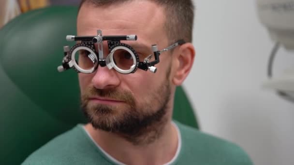 Homme à la réception d'un ophtalmologiste. Examen des yeux et sélection des verres de lunettes — Video