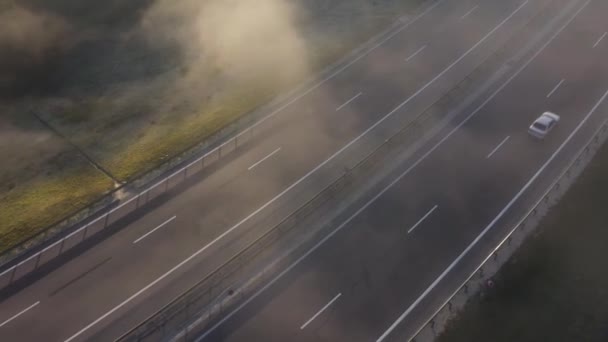 Vista desde la altura de la carretera en la que se mueven los coches. El camino está envuelto en niebla — Vídeos de Stock