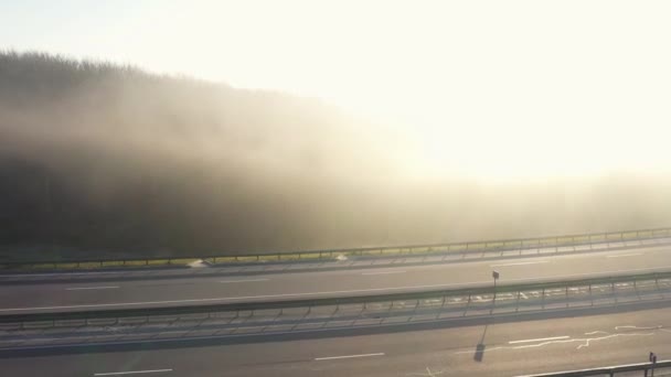 Вид с высоты дороги, по которой движутся автомобили. Дорога окутана туманом — стоковое видео
