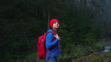 Kadın gezgin bir sırt çantası ile Nehri boyunca dağlarda yolda yürür ve çevresindeki manzara hayran