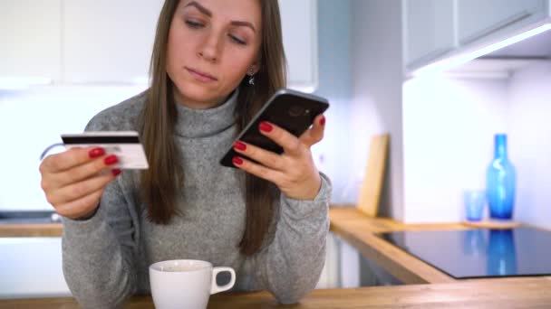 Mujer hace el pago en línea en casa con una tarjeta de crédito y un teléfono inteligente — Vídeo de stock