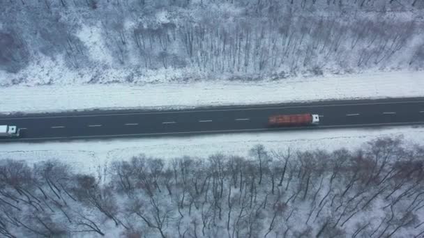 A légi felvétel a forgalom, az út áthalad a téli erdő télen — Stock videók