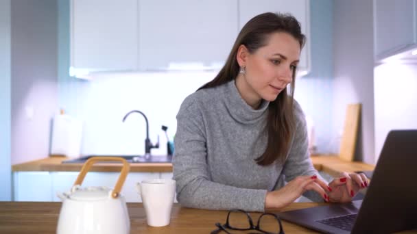 Mujer caucásica desayunando en la cocina y usando un portátil — Vídeo de stock