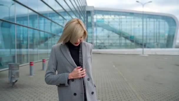 Ragazza bionda rotola una valigia vicino al terminal dell'aeroporto — Video Stock