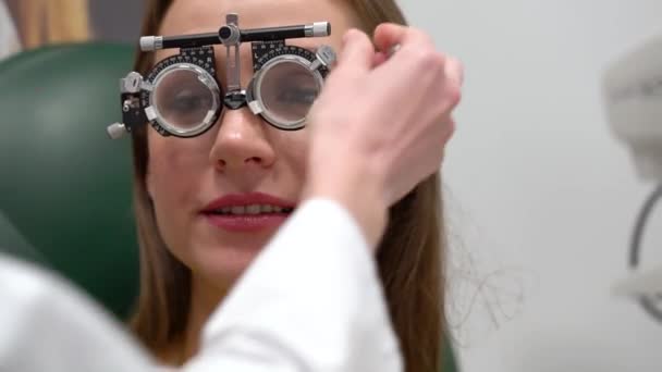 Vrouw bij de receptie van een oogarts. Oog onderzoek en selectie van brillenglazen — Stockvideo