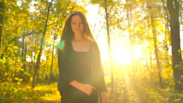 Hermosa chica vestida con vestido negro camina en el bosque de otoño y disfruta del buen tiempo . — Vídeo de stock