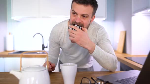 Mutfakta kahvaltı ve bir dizüstü bilgisayar kullanarak sakallı adam — Stok video