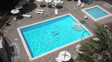 Bir kadın bir mavi mayo bir otel, villa veya apartman havuzda yüzer gibi en baştan görüntülemek