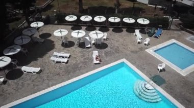 Bir tembel bir otel, bir villa veya bir daire havuz kenarında üzerinde mavi bir mayo bir kadın olarak üstten görünüm sunbathes